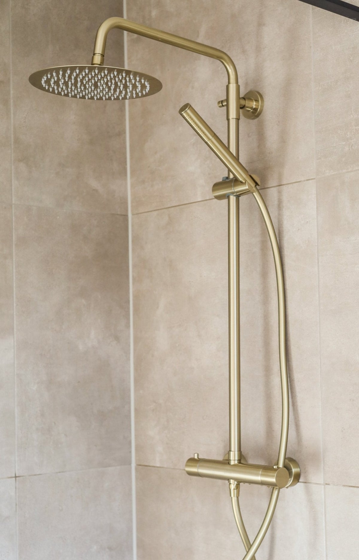 Ronde regendoucheset Novi in goud gemonteerd in een douche